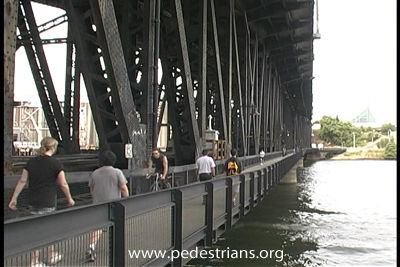 photo - pedestrians an bicyclists share walkway on RR bridge.